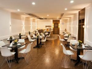 a restaurant with black tables and white chairs at Hotel Carlton in Duisburg