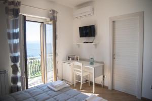 a bedroom with a bed and a desk and a window at Villa Caterina Affittacamere in Maratea