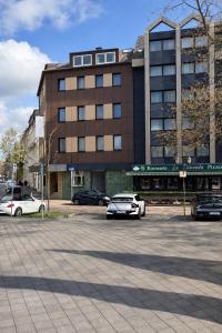 a parking lot with cars parked in front of a building at Hotel Carlton in Duisburg