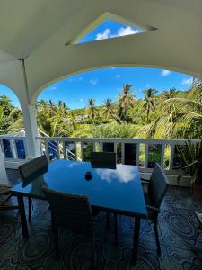 a table and chairs on a balcony with palm trees at La Villa Allamanda in Rodrigues Island