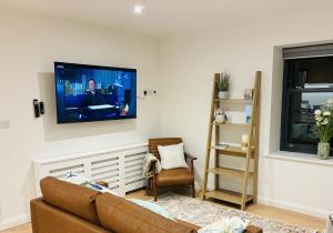 a living room with a couch and a tv on the wall at Clare Escape Ballycastle - Luxury town centre apartment, walk to beach & harbour, near Giants Causeway in Ballycastle
