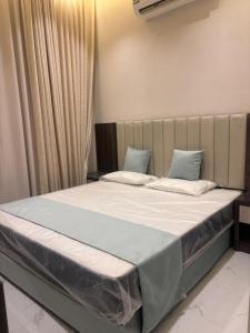a bedroom with a large bed with white sheets and blue pillows at استديو تراحيب لبن للضيافة in Riyadh