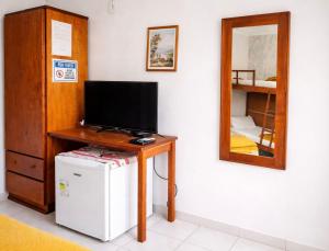 a room with a desk with a television and a mirror at Pousada Casarão Piúma in Piúma