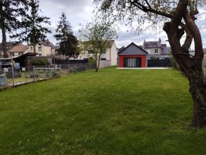 a grassy yard with a red and white house at Le petit marais in Le Mans