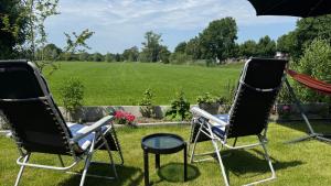 two chairs and an umbrella in a yard with a field at Janka B&B in Elim