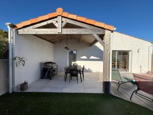 a wooden pergola with a table and chairs on a patio at Le Clos des Embruns in Chassiron