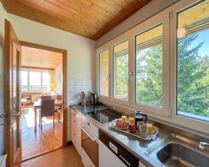 a kitchen with a sink and windows and a table at Villars - Charme et panorama in Ollon