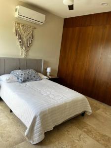 a bedroom with a white bed with a wooden wall at Chicxulub , oceanfront 3 recamaras in Chicxulub