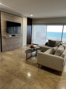 a living room with a couch and a flat screen tv at Chicxulub , oceanfront 3 recamaras in Chicxulub
