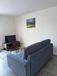 a living room with a blue couch and a piano at Le Clos des Embruns in Chassiron