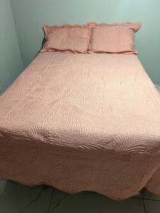 a bed with a pink comforter and pillows at Casa com área de lazer tranquila e espaçosa! in Campo Grande