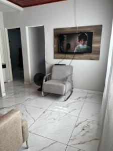 a living room with a chair and a tv on a wall at Casa com área de lazer tranquila e espaçosa! in Campo Grande