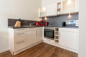 a kitchen with white cabinets and stainless steel appliances at Rodehuus Wohnung 2 in Borkum