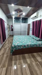a bedroom with a bed with a green comforter at Sakchi Gopal Ashram in Vrindāvan