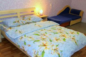 - une chambre avec un lit et une table de chevet dotée d'un couvre-lit bleu avec des fleurs dans l'établissement Apartment on Kharkovskoe Shosse 170 b, à Kiev