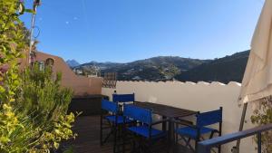 a wooden table and chairs on a deck with mountains at La Casita in Torrox