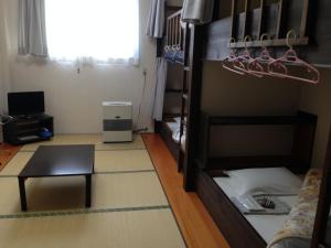 a room with a bunk bed with a desk and a table at Lodge Yodel in Senboku