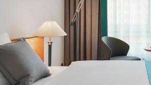 a bedroom with a bed with a lamp and a chair at Dorint Hotel Dresden in Dresden