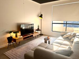a living room with a couch and a flat screen tv at Stylish Industrial City Retreat in Bowden