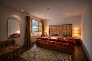 a bedroom with a bed and a chair and a window at THE NUN KUN Pahalgam in Pahalgām