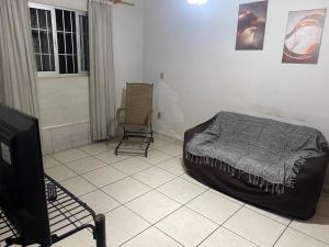 a bedroom with a bed and a tv and a chair at Casa 3 Quartos Espaço Luxemburgo in Anápolis