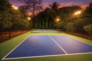 a tennis court at night with lights on at StayVista at Moksh Villa - BBQ & Jacuzzi in Alibaug