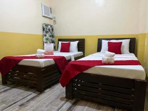 two beds in a room with red and white pillows at RTRoss Hotel in Masbate
