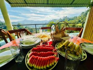 a table with plates of fruit on it with a view at Ayubowan, Ella in Ella