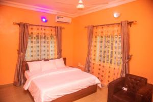 a bedroom with a bed and a chair at Classic Hills Hotel & Resort in Uyo