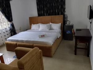 a bedroom with a large bed with a desk and a chair at Classic Hills Hotel & Resort in Uyo