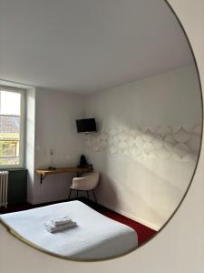 a mirror reflecting a bedroom with a bed and a chair at Santat Central hôtel in Bellac +11 photos
