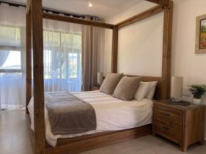 a bedroom with a wooden canopy bed and a window at 127 Clarens Golf Villa in Clarens
