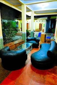 a lobby with black ottoman chairs and a glass table at Penginapan Barokah in Kemadang