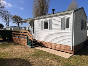 a white house with a fence next to it at Mobile Home à Louannec in Louannec