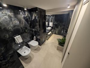 a bathroom with a toilet and a black marble wall at Twentyseven Luxury Suite in Catania