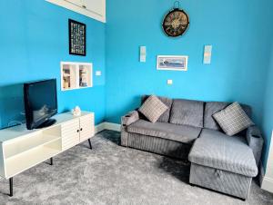 a blue living room with a couch and a tv at Commodore Guesthouse, Seaside Holiday Suites in Rothesay