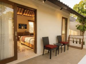a bedroom with a bed and two chairs at Sardja Uluwatu in Uluwatu +56 photos