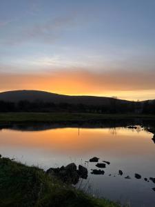 a sunset over a lake with rocks in the water at Beautiful Beach Side Bungalow in Galway