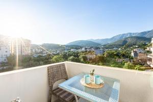 a table on a balcony with a view of a city at Shiny 2 Central Stay in Himare