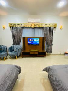 a living room with a tv and two beds at Amada Family Guest House in Karachi
