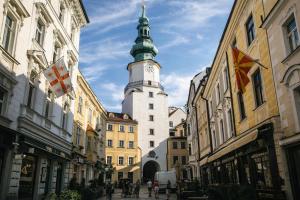 a tall tower in the middle of a street with buildings at Štúr Apartment Michalská in Bratislava
