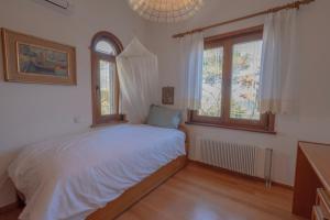 a bedroom with a bed and two windows at Dual bay views by ΜΡS in Dhaskalión