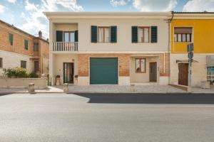 a house with a green garage door on a street at L'Acqua e la Pietra in Rapolano Terme