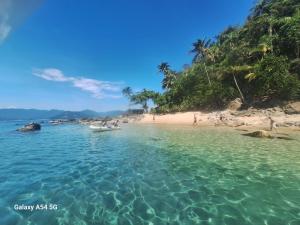 a beach with a boat in the water at Alma Surf House in Boicucanga