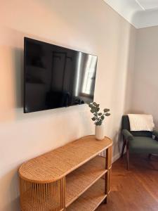 a living room with a table and a television on a wall at Maison Louisa in Saint Paul de Vence