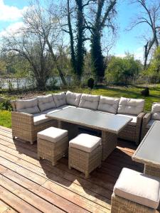 a couch and a table on a wooden deck at Le Clos des Berges de l'Ain in Charnoz
