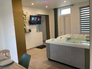 a bathroom with a tub with a tv in it at SPA La Maison du Bonheur Suite avec Spa prive pres d Arras in Roeux