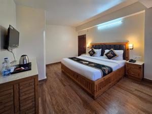 a hotel room with a large bed and a television at Kavin Uphar The Mall Road in Shimla