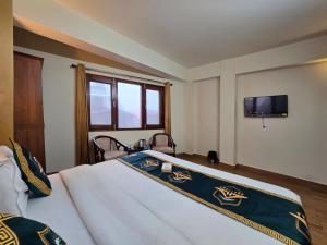 a bedroom with a bed and a tv on the wall at Kavin Uphar The Mall Road in Shimla