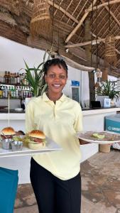 Eine Frau, die ein Tablett mit zwei Hamburgern darauf hält. in der Unterkunft SOFIA SEA VIEW - Beach Boutique Hotel by Sofia Collection in Pwani Mchangani